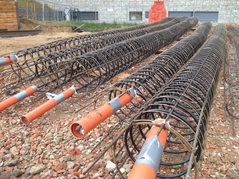 Obr. 1 Výstužné koše vŕtaných pilót pripravené na stavenisku. Pri energetických pilótach sa do koša pred betonážou fixuje výmenník tepla (potrubie PE-Xa), takže nosný základový prvok zároveň slúži na odber a ukladanie tepla. Foto: GE-TRA s.r.o., dostupné z https://www.ge-tra.cz/problematiky/zemni-plosne-kolektory-energeticke-piloty